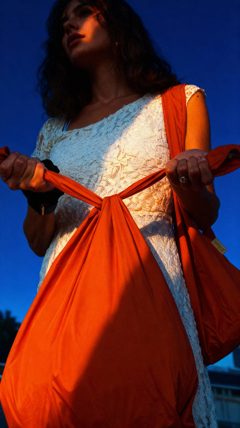 Woman holding an orange bag against a blue sky