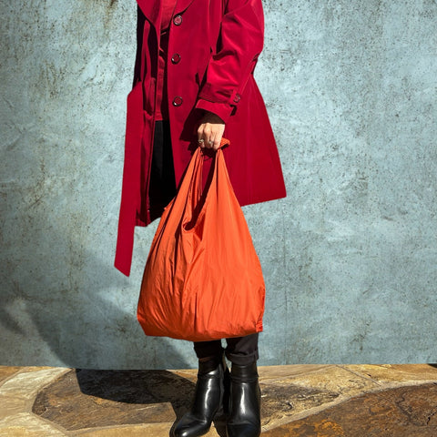 model in a red coat holding a red shopping tote