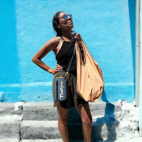 A shopper wearing a blue Toaty zipper case and tan tote bag